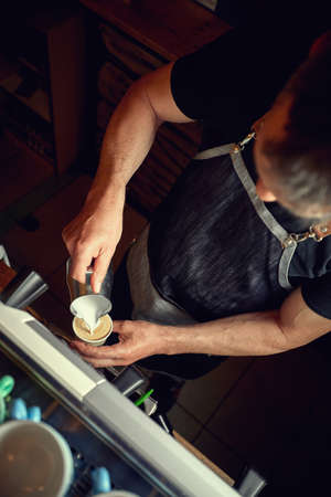 Man pouring steamed milk to a cappuccino cup. professional coffee bar workerの写真素材