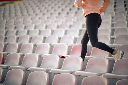 cropped image of young female running between seats in stadiumの写真素材