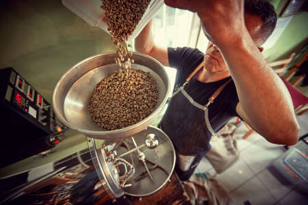 Man drip raw coffee over a coffee roasting machine.の写真素材