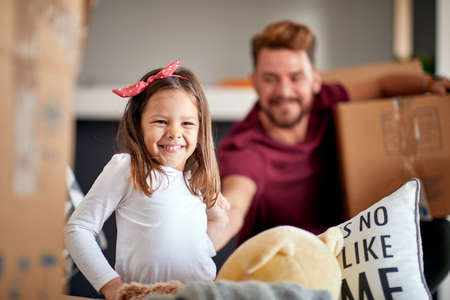 A little daughter is having a good time with her father in the new home while unpacking things in a cheerful atmosphere. Home, family, movingの写真素材