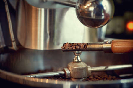 spatula with raw coffee beans near special equipment.の写真素材