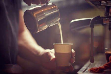 pouring milk   in fresh coffee cup to go.の写真素材