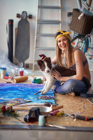 A sexy and attractive female artist is sitting on the floor in a relaxed atmosphere in the studio...