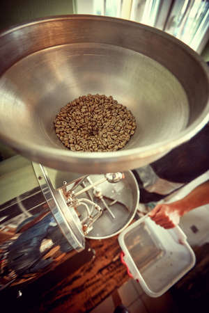 Close up of inserting fresh coffee for roasting process