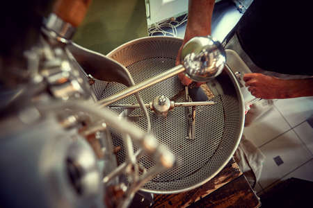 Close up of inserting fresh organic coffee for roasting processの写真素材