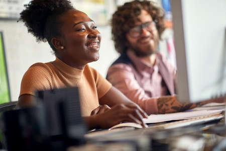 Young colleagues are in a good mood while working in a cheerful atmosphere at office together