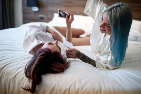 Cheerful lesbian couple sharing a pregnancy test results togetherの写真素材