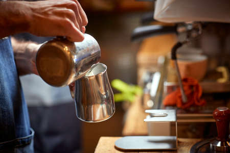 A barman is preparing a milk to make an aromatic and fragrant espresso in the apparatus. Coffee, beverage, barの写真素材