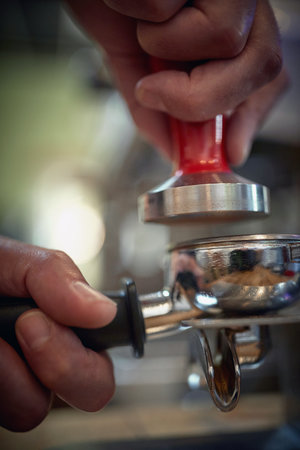 Close-up view of barman's hands who is pressing fragrant and aromatic ground coffee for an espresso. Coffee, beverage, barの写真素材