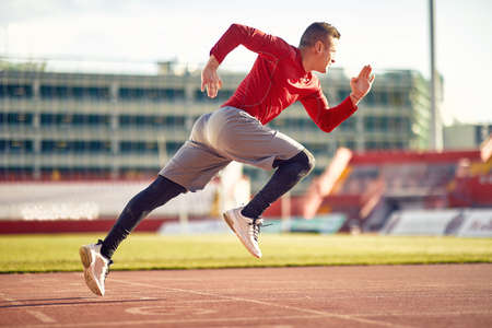 A young man in a low start at an athletic training on a beautiful day at the stadium. Sport,...