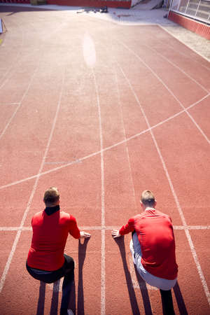 two men at starting line of athletic track ready to start the race. Conceptual image of competition.の写真素材