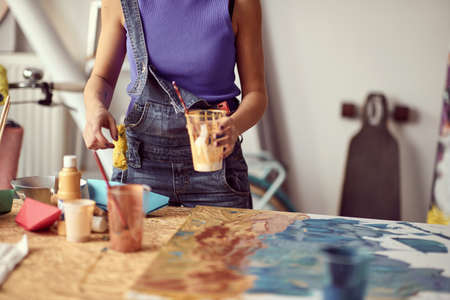 A young female artist is mixing paints while working on a new painting in a pleasant atmosphere in the studio. Art, painting, studioの写真素材
