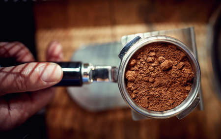 Close-up of an utensil full of ground coffee ready for making an aromatic and fragrant espresso....