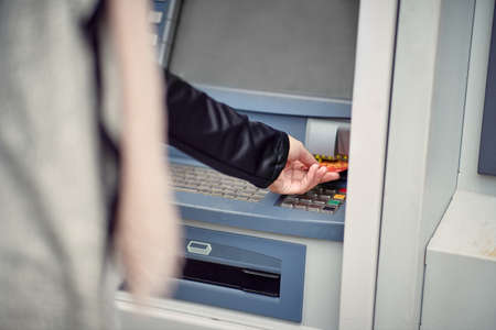Close-up of a woman using a cash machine on the street. Walk, ATM, cityの写真素材