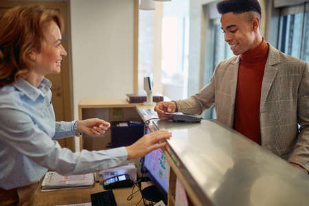 Business man paying with card to a smiling female receptionistの写真素材