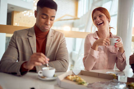 woman laughing at funny joke with diverse coworkers.friendly work team enjoying at lunch togetherの写真素材