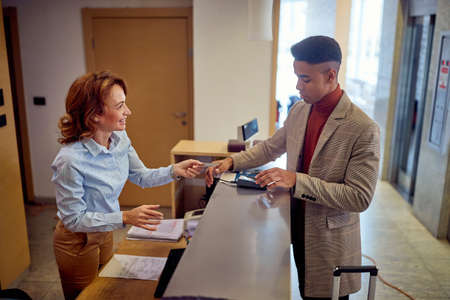 Man paying with card to a smiling female receptionistの写真素材