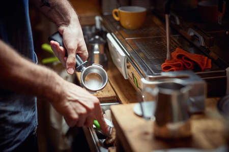 A barman behind the bar beside an espresso apparatus in a working atmosphere. Coffee, beverage, barの写真素材