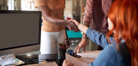 Professionals shaking hands together in the office; Making a deal conceptの写真素材