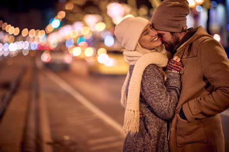 Couple Hugging Standing On A Street Decorated With Winter Lights