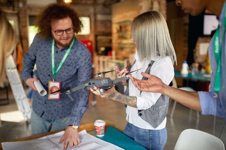 A group of young creative colleagues in a working atmosphere in the office is analyzing a drone they will use in a projectの写真素材
