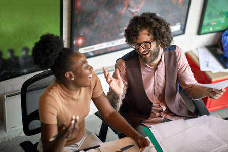 Young colleagues are having a nice talk while working in a pleasant atmosphere in the office togetherの写真素材