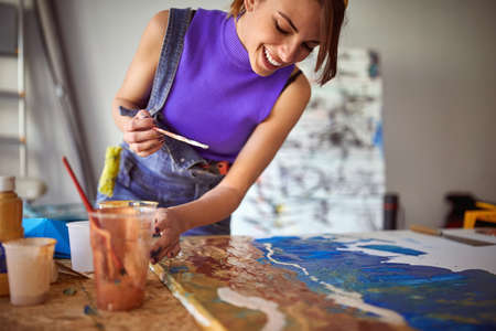A happy young female artist is painting in a pleasant atmosphere in her studio. Art, painting, studioの写真素材