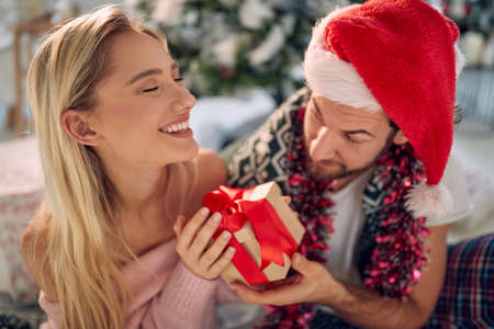 Couple exchanging Christmas gifts.Man giving  Christmas gift his happy girlfriend.の写真素材