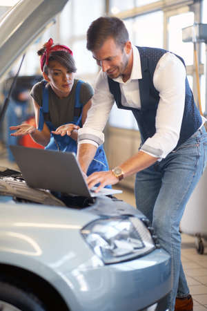 Girl mechanic learning in the car workshop with colleagueの写真素材