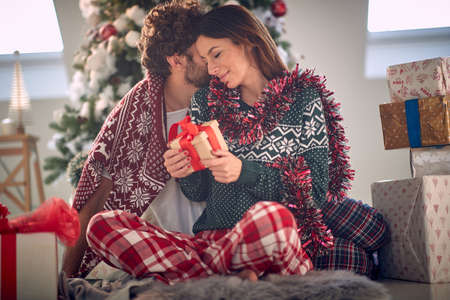 Smiling romantic Couple hugging around christmas tree at homeの写真素材