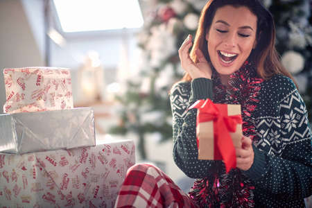 Happy caucasian woman opening gifts on a Christmas morningの写真素材