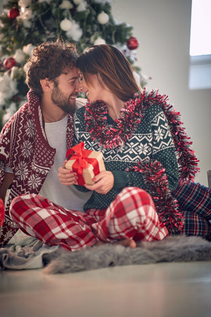 Festive caucasian couple exchanging Christmas gifts on a Christmas morningの写真素材