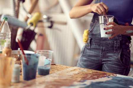 A young female artist is preparing the paint while working on a new painting in a pleasant atmosphere in the studio. Art, painting, studioの写真素材