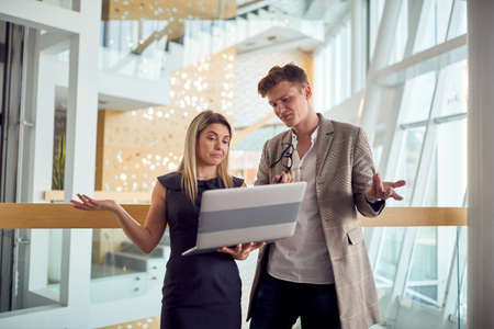 Two young business colleagues are not satisfied with laptop content they watching together in a...