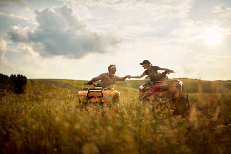 A young couple in love is riding a quad on a beautiful sunny day in the nature. Riding, relationship, nature, activityの写真素材