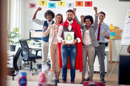 A group of cheerful employees in a pleasant atmosphere in the office enjoy posing for a photo to...