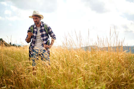 young man on the nature listens to music.happy man with backpack and smartphone outdoorsの写真素材
