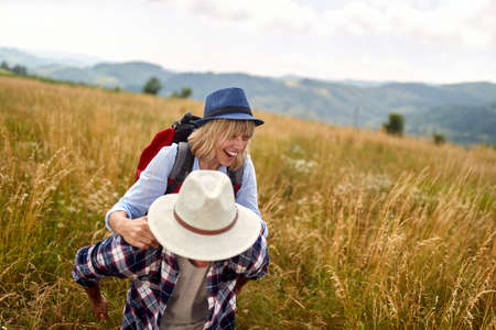 A young happy couple in love is having a good time while walking a meadow on a beautiful sunny day. Hiking, nature, relationship, togetherの写真素材