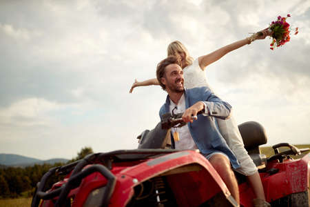 Happy young bride and groom enjoying a quad atv vehicle at nature