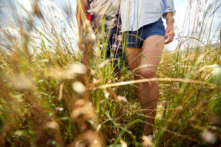 Close up shot of couple hiking in field, through grass. Nature outdoors. Caucasian couple. Sport,...