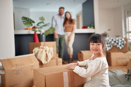 cute little asian girl  looking at camera, smiling, with her parents in the background. eye contactの写真素材