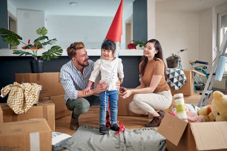 mom and dad playing with their daughter with paper rocket on her back.  multiethnic familyの写真素材