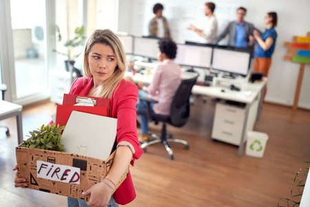 A young female clerk in tears leaves the office after she is being fired from the job she likes. Employees, job, officeの写真素材