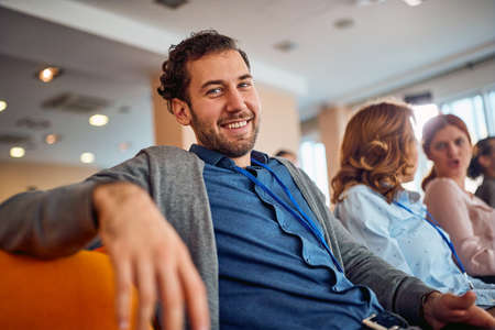 A young businessman is posing for a photo while following a business lecture in a pleasant...