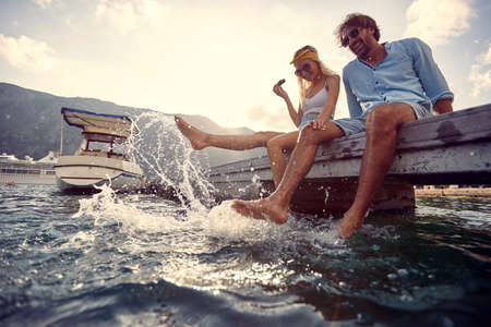 Young couple in love flirting and enjoying dangling legs in the lakeの写真素材