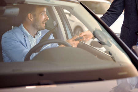 Buyer in car taking key of a new car from salesman in auto sales salon