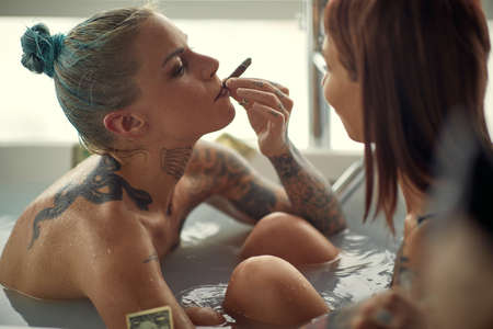 Hot lesbian couple having fun together in bath tub; Hedonistic lifestyleの写真素材