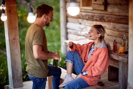 Smiling young man ad woman talking and relaxing on cozy balcony in nature.の写真素材