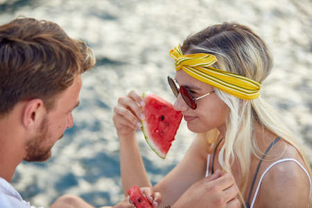 A young couple in love enjoying a juicy watermelon on a beautiful day on the seaside. Love,...