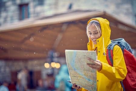 A young girl is following the map while walking the old city on a rainy day during a vacation on the...